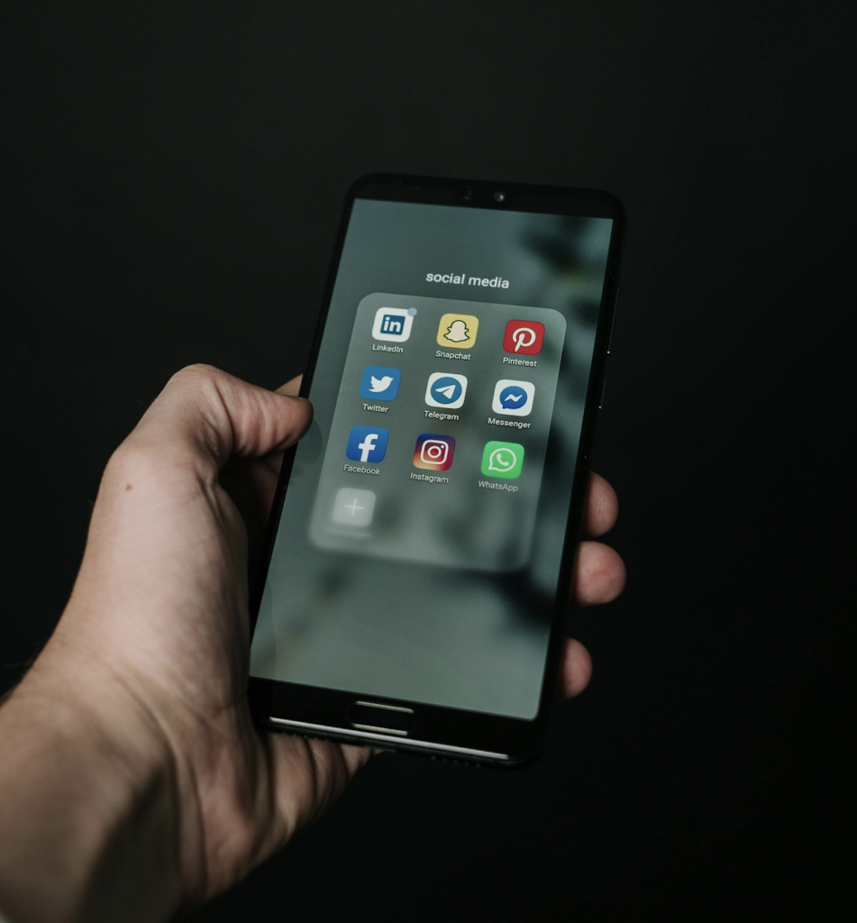Une personne qui tient dans sa main un téléphone où on peut voir différents médias sociaux.