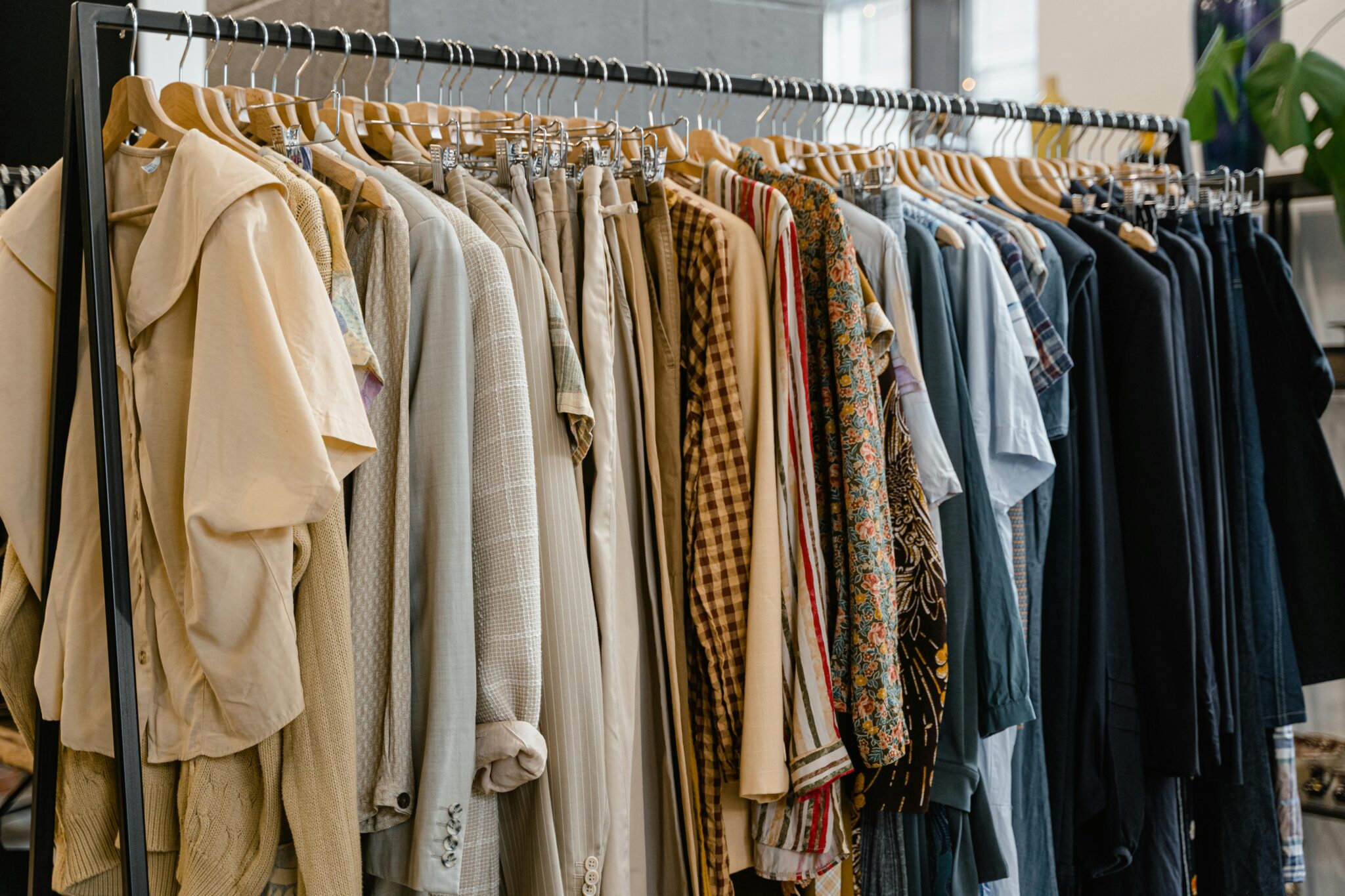 Une raque de vêtements de couleur beige, orangé, bleu et noir. Autant des haut que des bas.