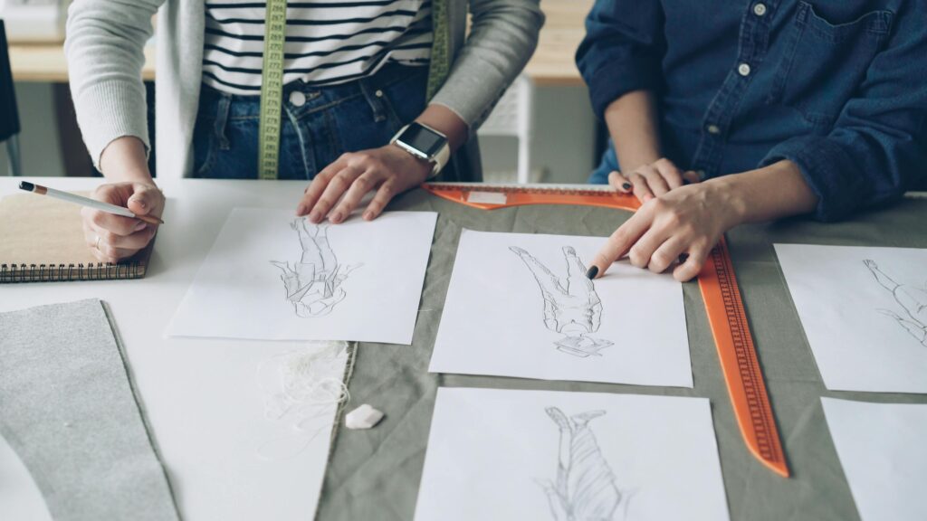 Deux personnes qui sont des stylistes qui comparent deux dessins de femmes